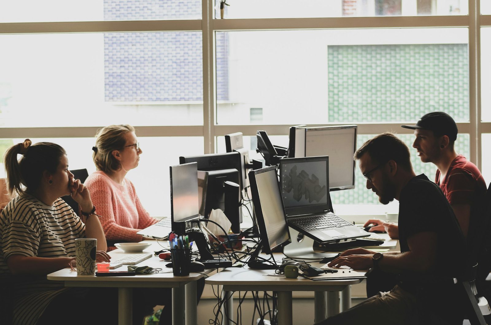 A studio team at their desks, working at monitors in a daylit office
